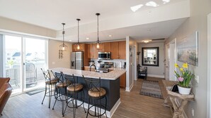 Una cocina moderna con una isla central, taburetes de bar e iluminación colgante.