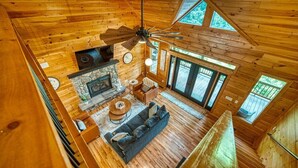 A wooden cabin interior with a fireplace, sofa, and dining area. - Meribel-Hot tub-Fire pit-Amazing Views (Young Harris)