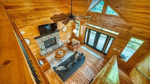 A wooden cabin interior with a fireplace, sofa, and dining area.