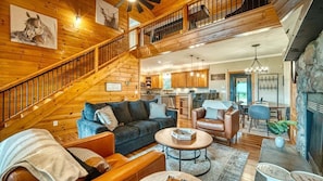 A spacious living area with a staircase, a kitchen, and a fireplace.