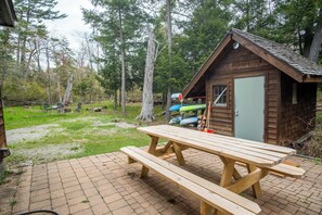 Een houten chalet met een picknicktafel ervoor, omringd door bomen.
