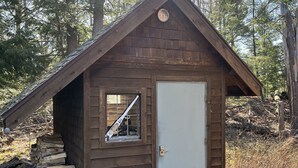 Eine kleine Holzhütte mit geneigtem Dach, einem Fenster und einer Tür.