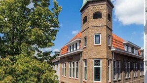 A hotel with a prominent tower, outdoor seating area, and a brick facade. - Hotel de Koppelpaarden (Lichtenvoorde)