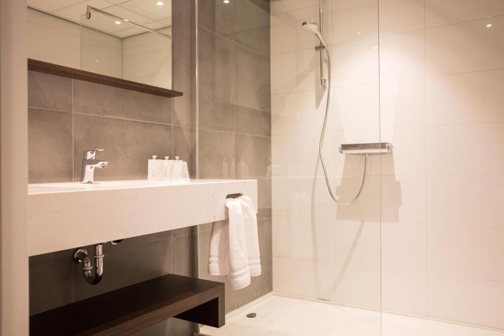 Deluxe kamer | Badkamer | Een douche, een haardroger, handdoeken, zeep