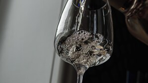 A wine glass being filled with a dark liquid, likely wine, in a dimly lit setting. - Hotel de Koppelpaarden (Lichtenvoorde)