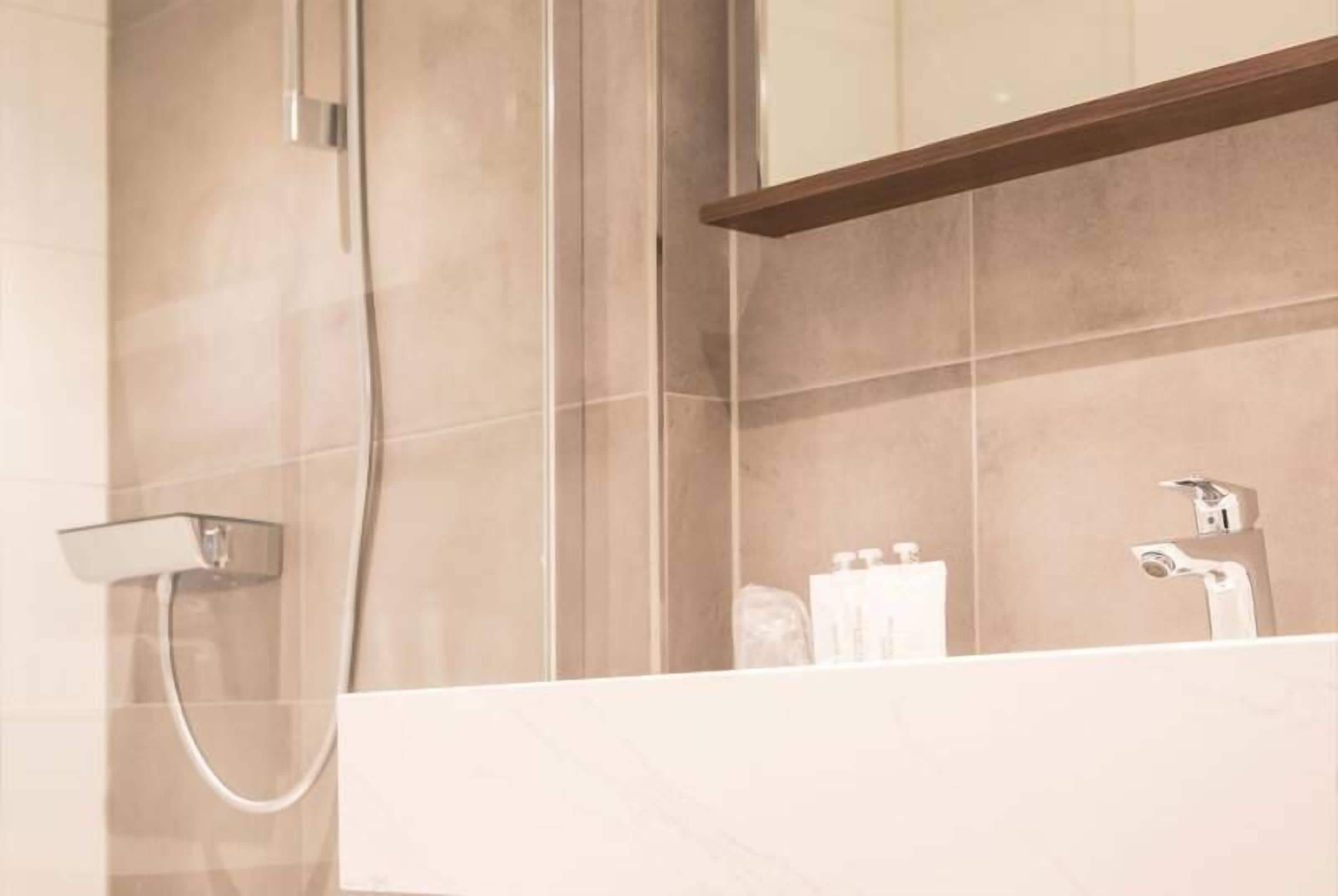 A bathroom with a shower, a sink, and a mirror.