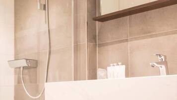 A bathroom with a shower, a sink, and a mirror.