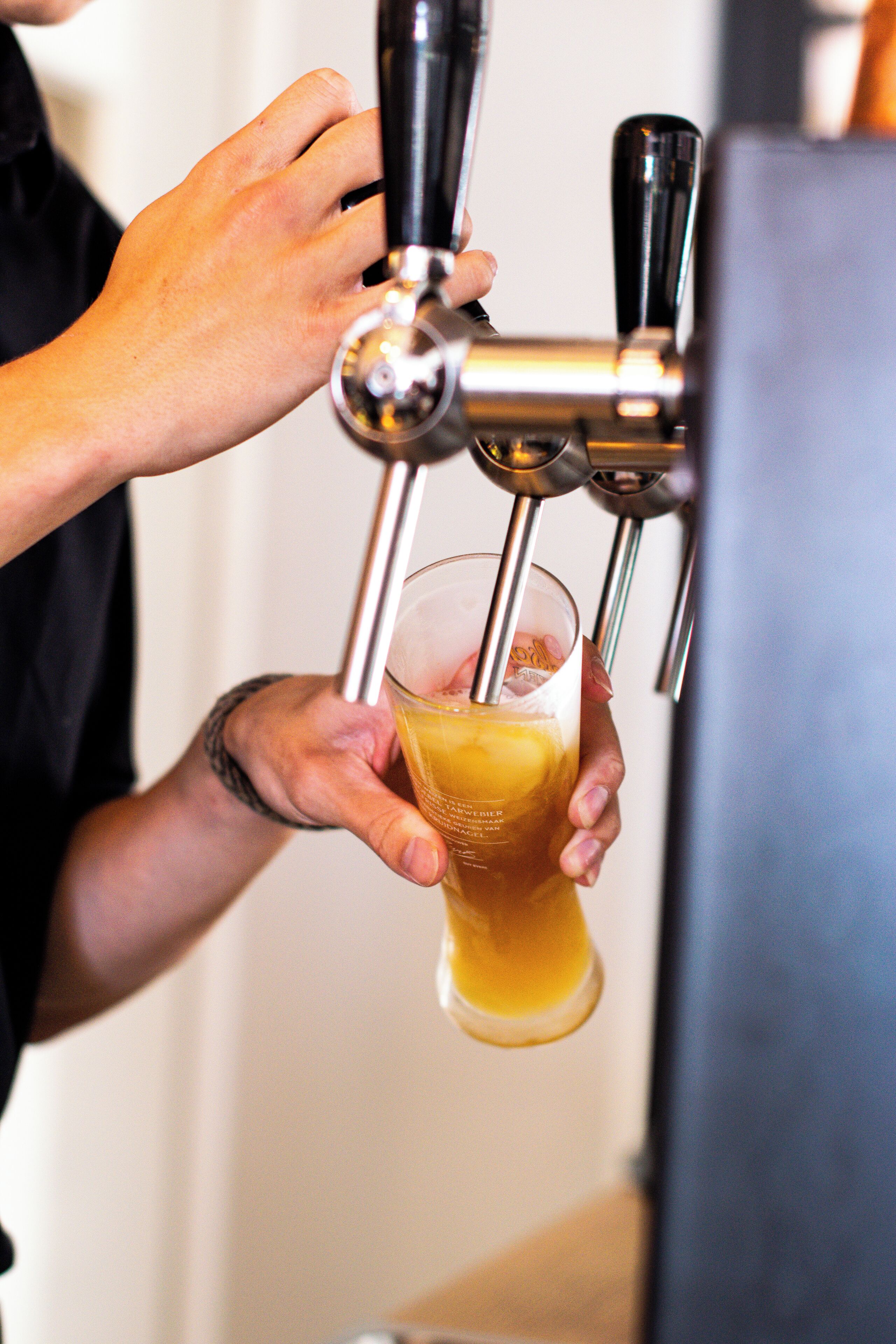 Una mano che tiene un bicchiere sotto un erogatore di birra.
