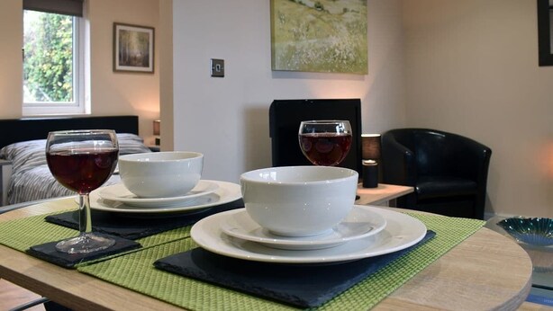 Uma área de refeições com uma mesa posta para dois, com tigelas brancas e copos de vinho.