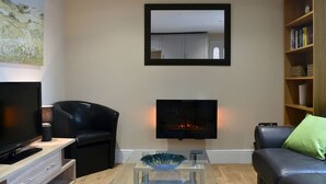 Uma sala de estar moderna com televisão de tela plana, sofás de couro, uma mesa de centro e uma estante de livros.
