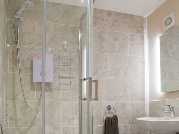 A modern bathroom with a glass-enclosed shower, a sink, and a mirror.