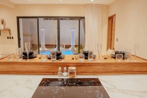 A dining area with a wooden table set for two, featuring clear glassware and plates.