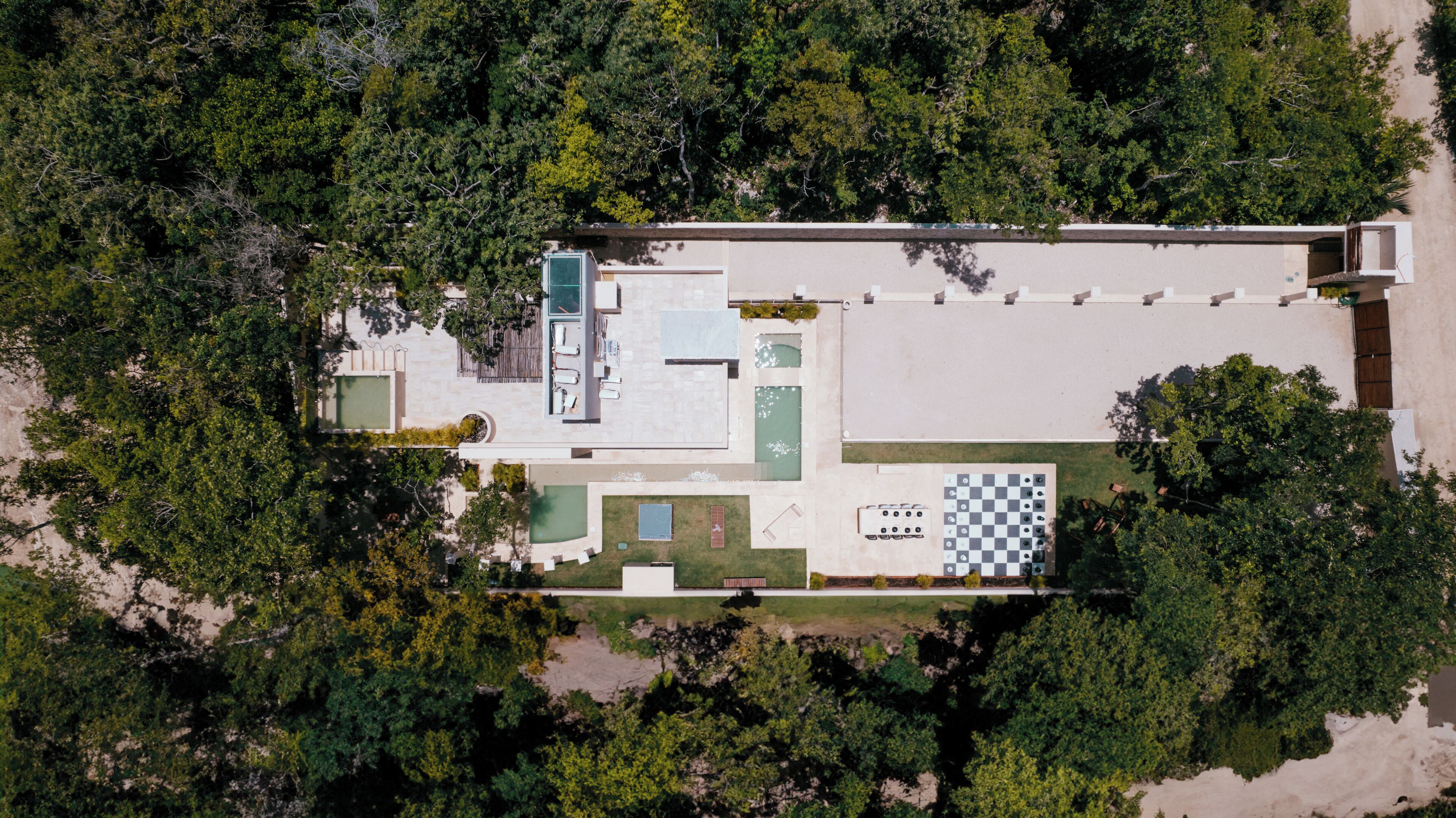 Vue aérienne d’un complexe hôtelier doté d’une piscine, d’un espace de détente en plein air et d’une table d’échecs.