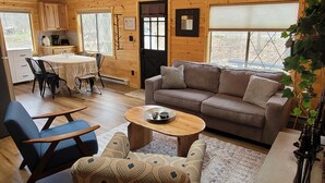 Interior acogedor de una cabaña con zona de comedor, sofá y mesa de centro.