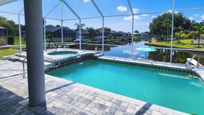 A swimming pool with a hot tub, surrounded by a covered patio area. - Five Star 3bd Waterfront Canal Home w/ Private Pool/Spa & Boat Dock. (Palm Coast)
