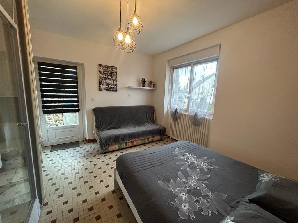 A bedroom with a bed, a window, a radiator, and a door.