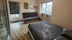 A bedroom with a bed, a window, a radiator, and a door.