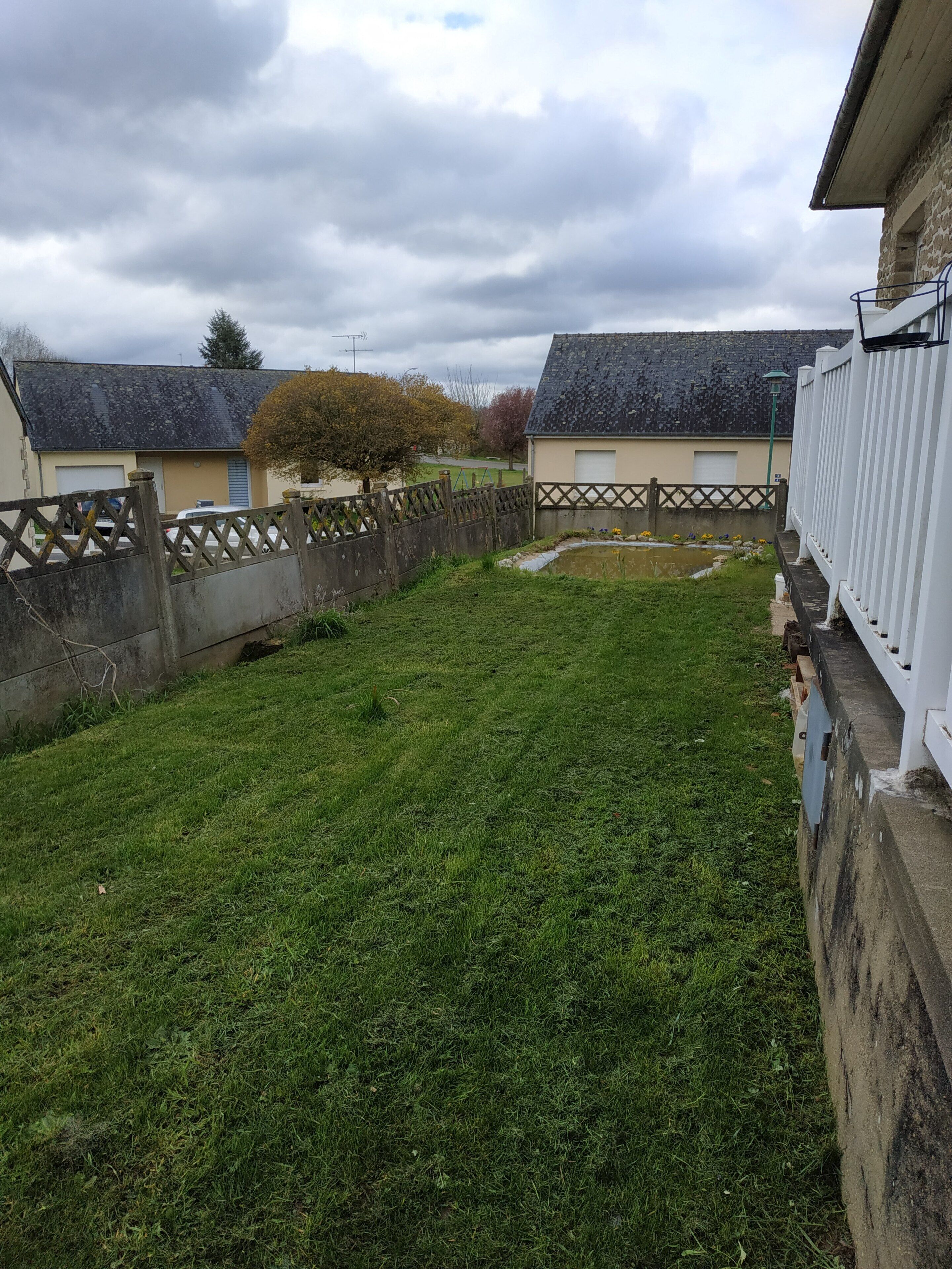 A residential area with a grassy yard, a wooden fence, and houses with sloped roofs.