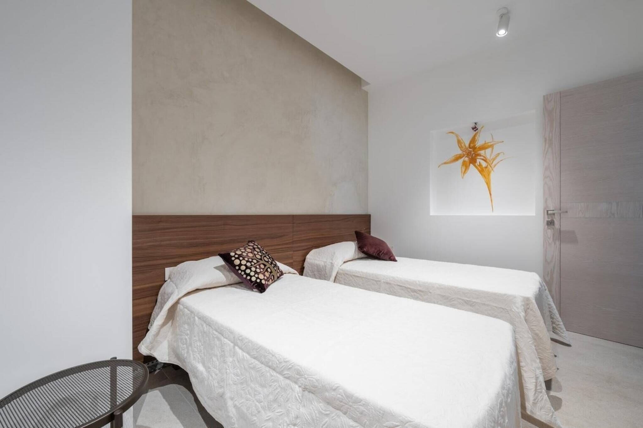 Une chambre d’hôtel avec deux lits, une chaise et une plante fixée au mur.