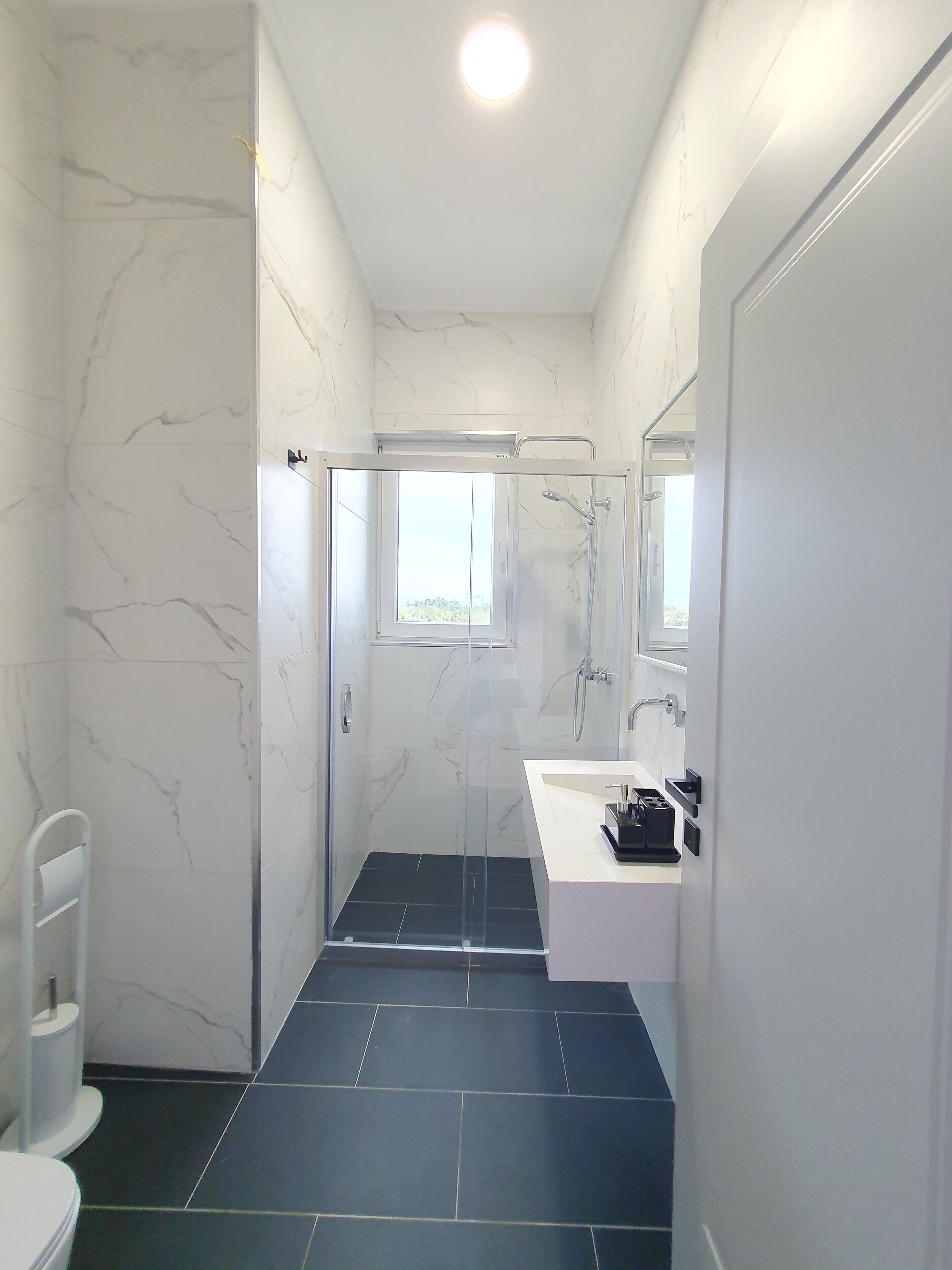 deluxe room | bathroom | shower, rainfall showerhead, hair dryer, slippers