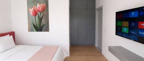 Un dormitorio con una cama, un cuadro de tulipanes, un televisor y un armario.
