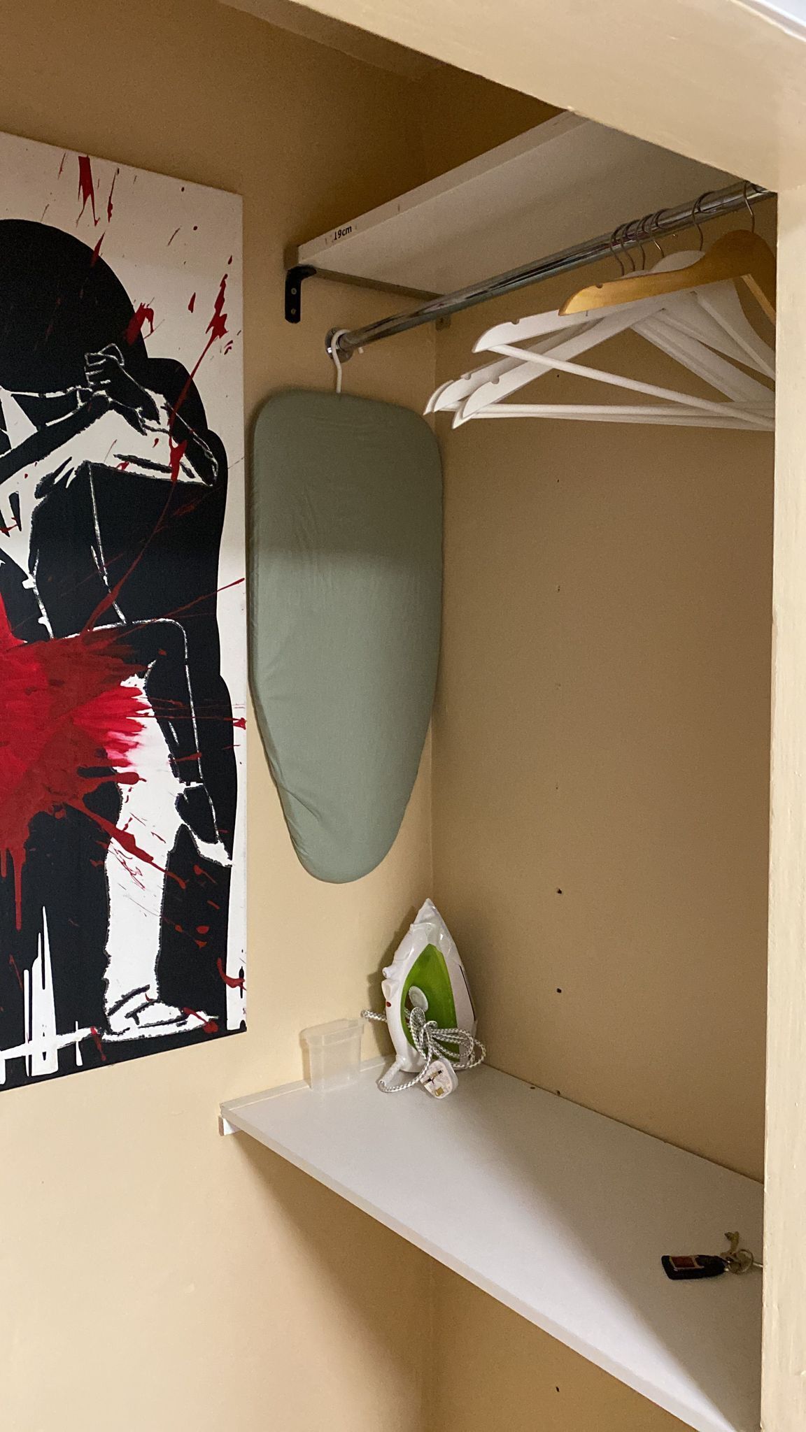 A bathroom with a large abstract painting, a white shelf, and a hanging towel rack.