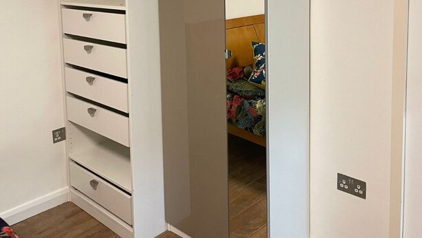 Une pièce dotée d’une armoire comprenant de nombreux tiroirs et une porte-miroir.