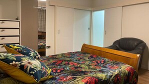 Une chambre à coucher avec un lit, une chaise, une armoire et un miroir.