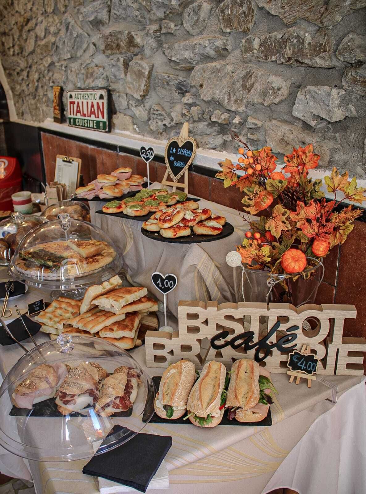 A buffet table with various Italian dishes, including pizzas and sandwiches, priced at 1.00 and 2.50.