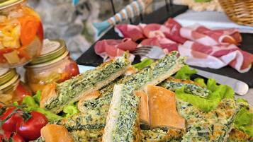 Una mesa con diferentes alimentos, como pan, tomates y frascos de pepinillos.