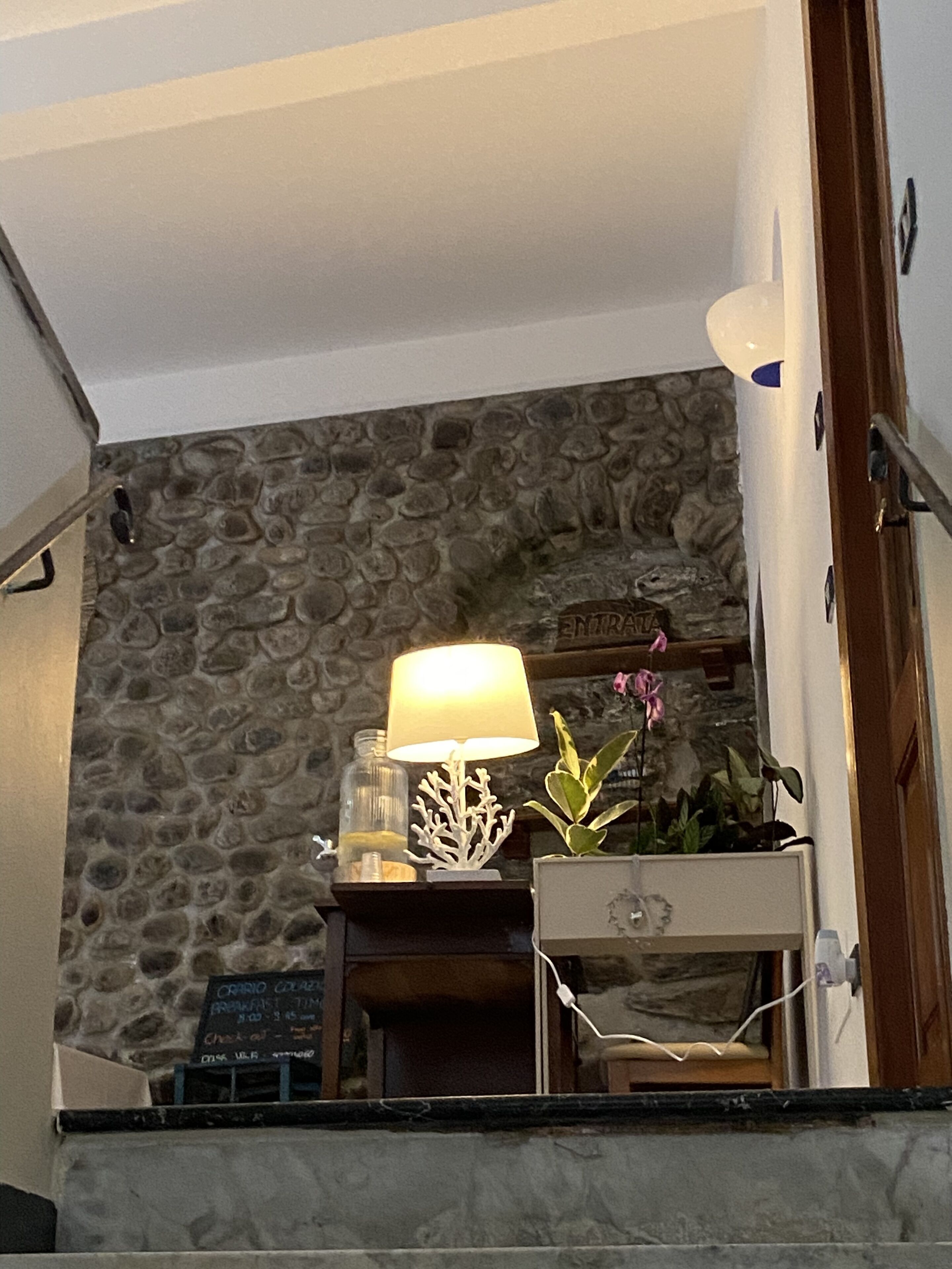 Eine Steinsäule mit einer Lampe und einem kleinen Tisch mit einer Pflanze.