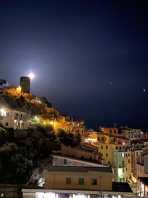 A coastal town at night with illuminated buildings, a prominent tower, and a clear view of the sea. - Pensione Sorriso (Vernazza)