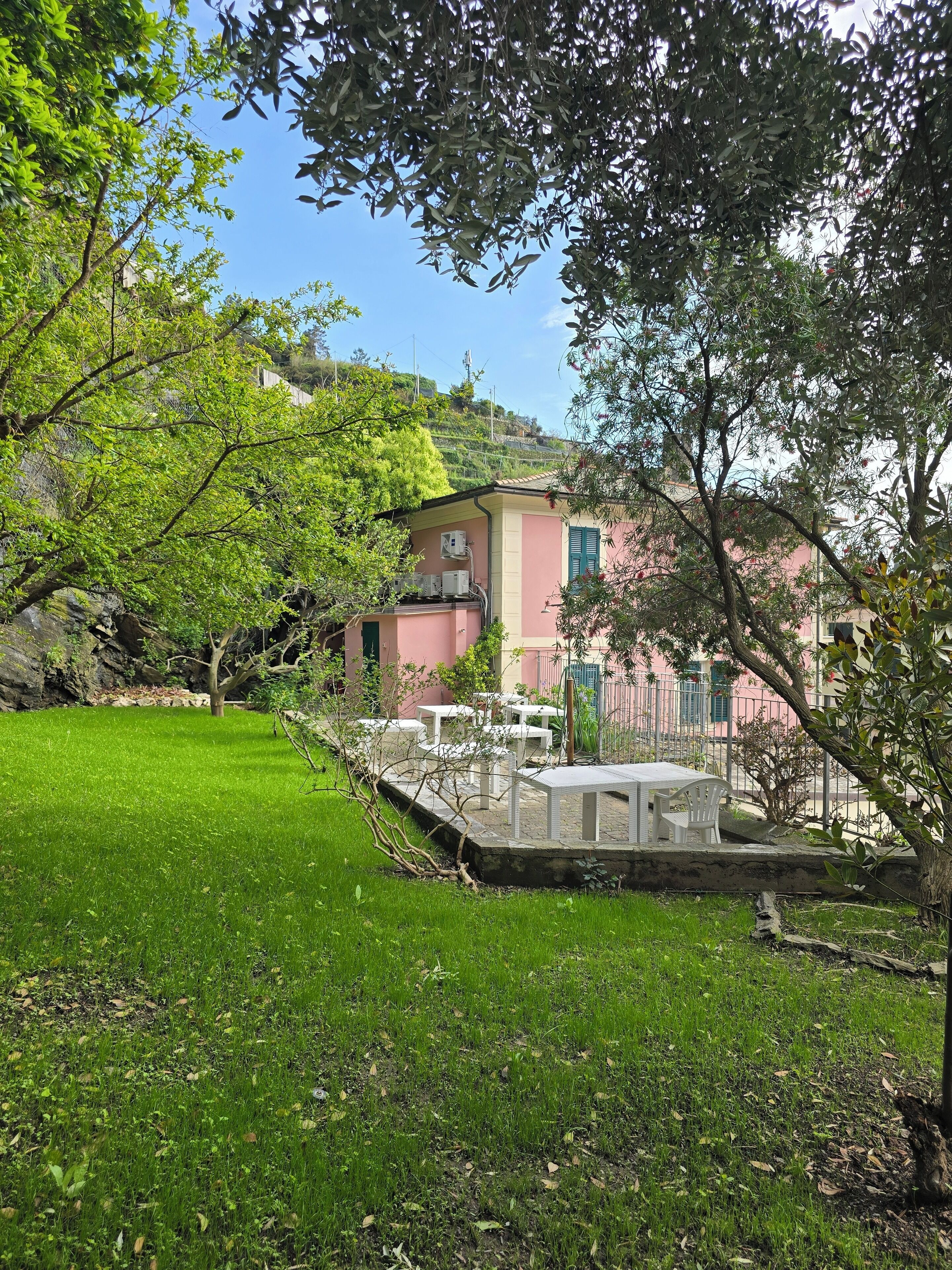A pink building with outdoor seating and a grassy area.