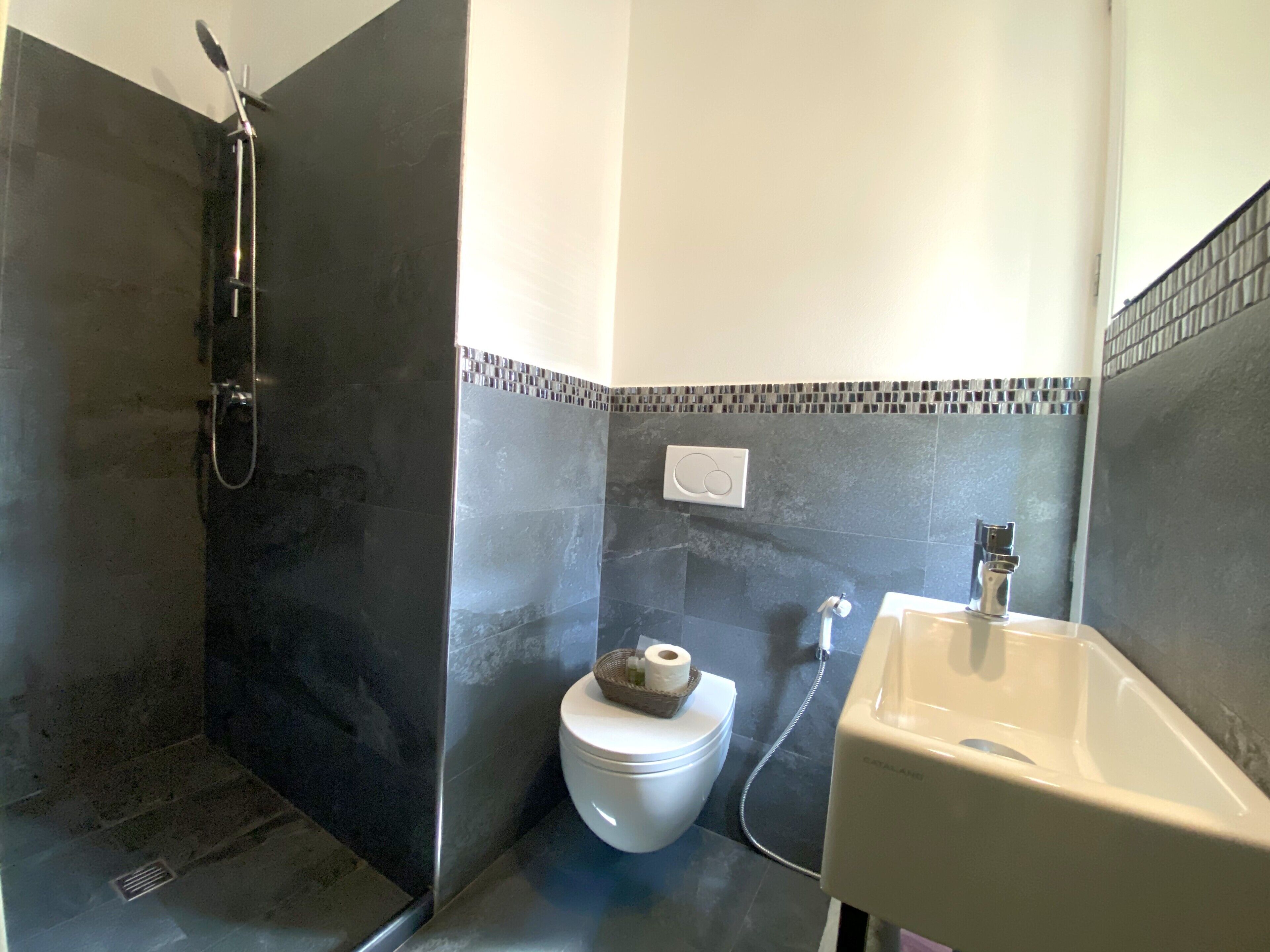 A bathroom with a shower, toilet, and sink.