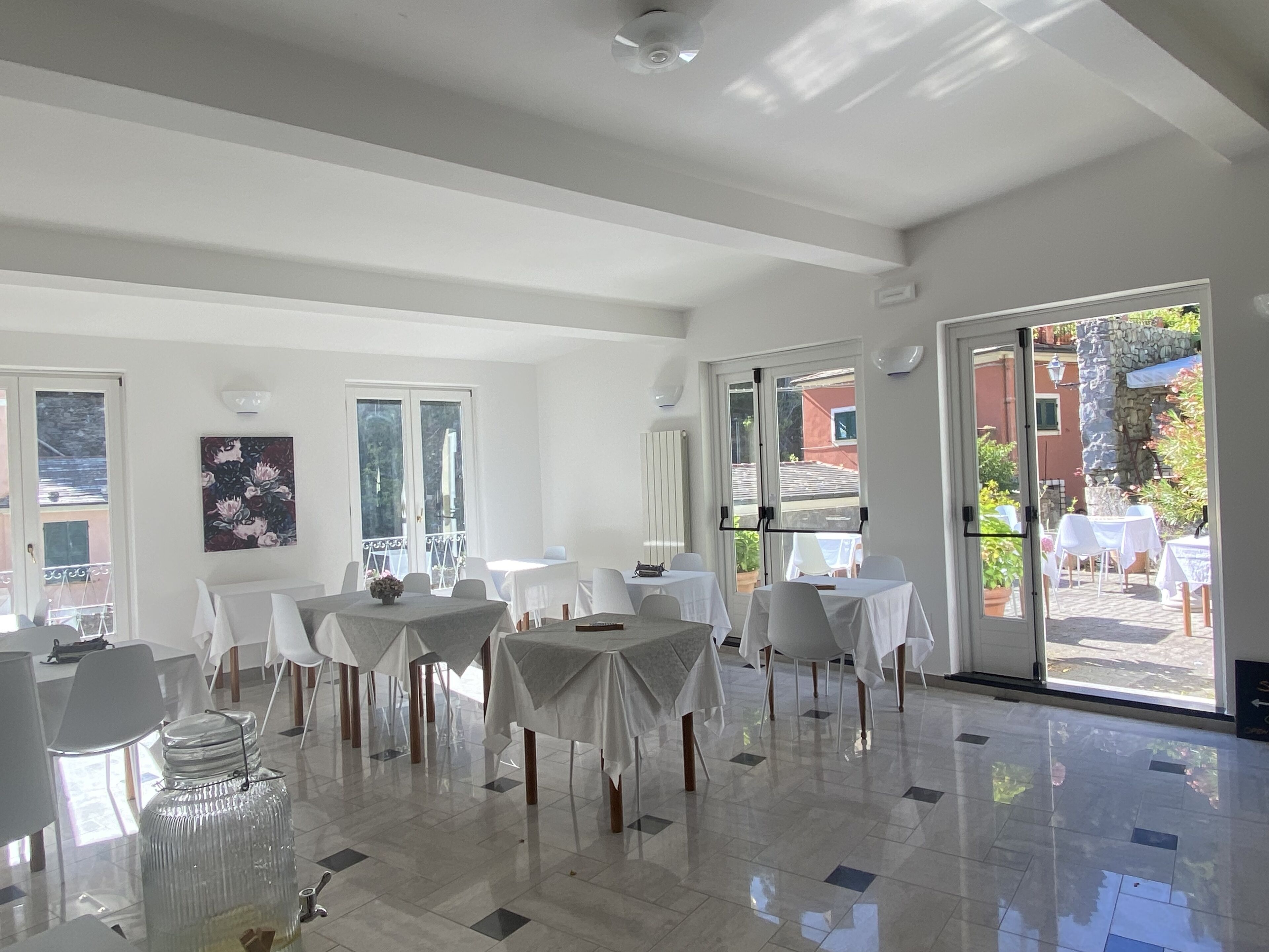 A spacious dining area with multiple tables and chairs, large windows, and a view of the outside.