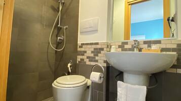 Ein Badezimmer mit Toilette, Dusche, Waschbecken und Handtuchhalter.