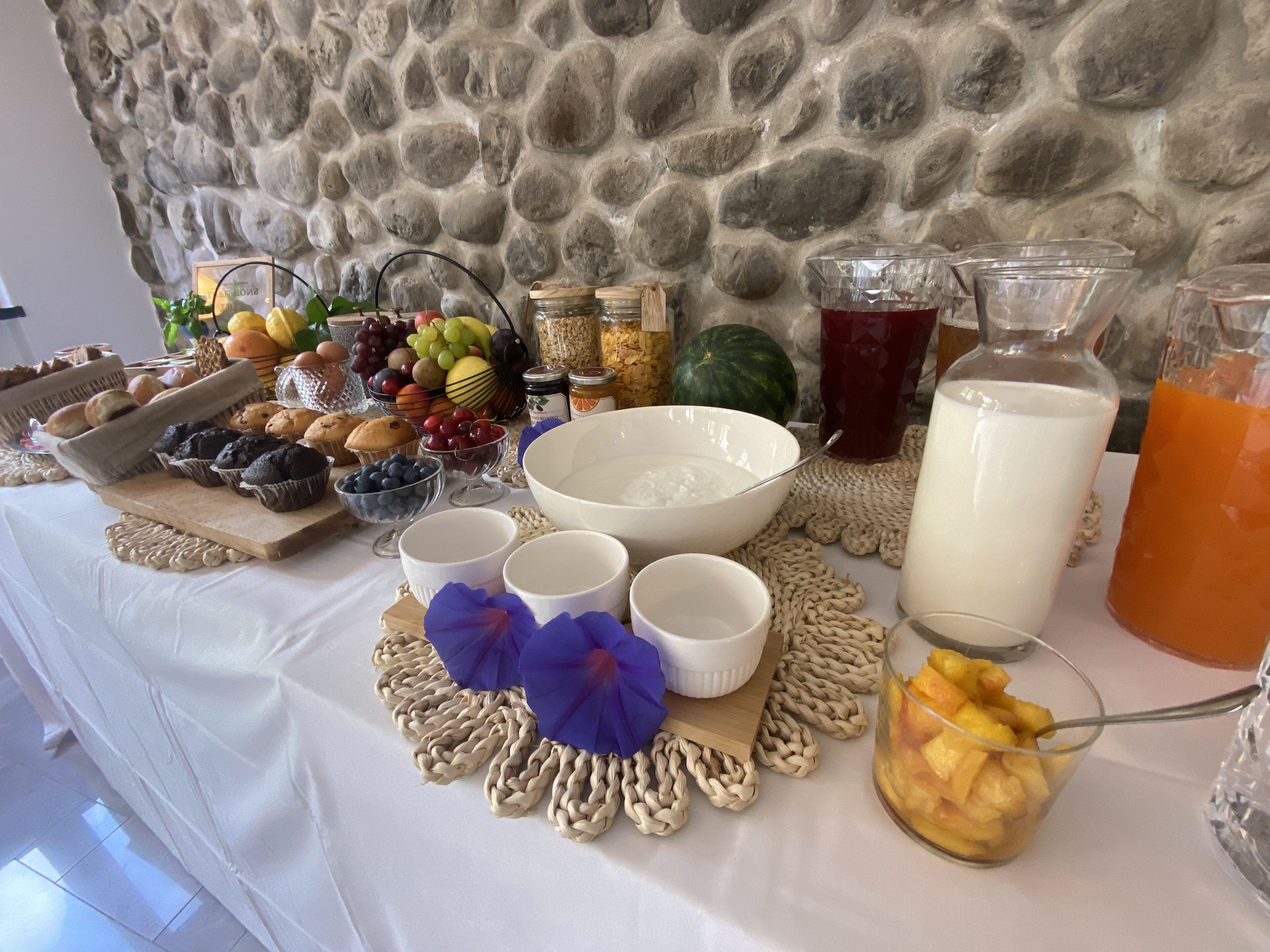 A buffet table with various food items, including fruits, muffins, and beverages.