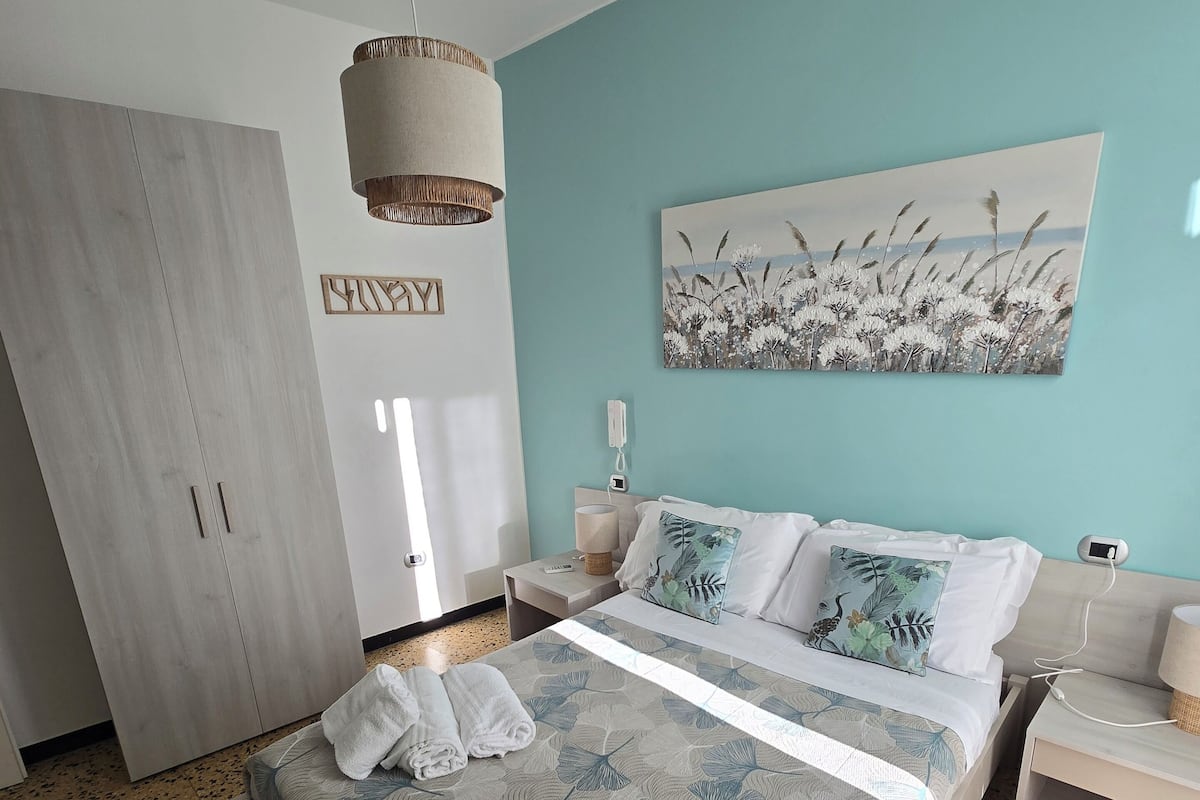 A bedroom with a bed, a nightstand, a wardrobe, and a painting on the wall.