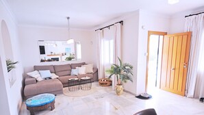 A living room with a sofa, coffee table, and a dining area with chairs and a table. - Pinomar 1A (Nerja)