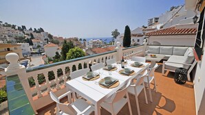 A terrace with a dining setup overlooking a coastal cityscape. - Pinomar 1A (Nerja)