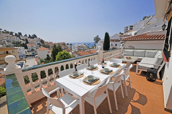 A terrace with a dining setup overlooking a coastal cityscape. - Pinomar 1A (Nerja)