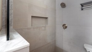 Une salle de bain moderne avec une douche, des toilettes et un comptoir en marbre.