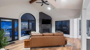 A modern living room with a large sofa, a fireplace, and a ceiling fan. - Le Chamonix A 2 Bedroom Condo (Mountain Village)