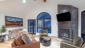 Un salon moderne avec une cheminée, un canapé en cuir et une grande fenêtre offrant une belle vue.