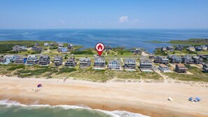 Vista aérea de una zona residencial costera con casas, una playa y una vista despejada del océano.