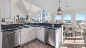 Una cocina moderna con una isla grande, electrodomésticos de acero inoxidable y vistas al océano.