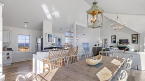 Una cocina espaciosa con una isla grande, muebles blancos y vistas al exterior.