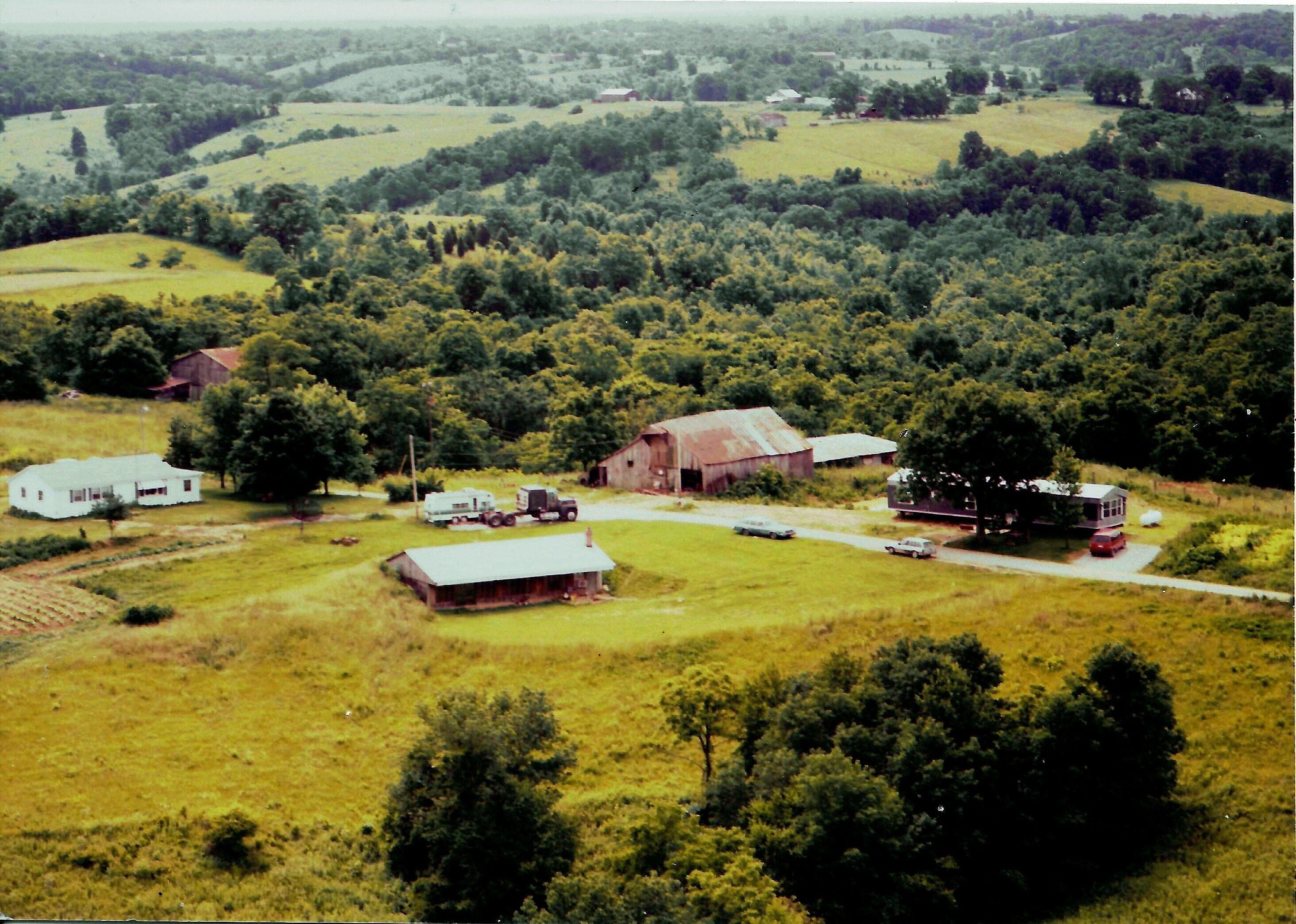 Paisaje rural con graneros, una casa blanca y un camión.