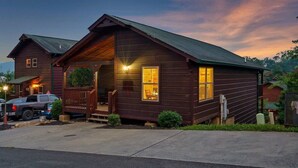 A wooden cabin with a porch, a garage, and a small front yard. - Free Dollywood Tix/Pool/5Min2Dollywood/Pool Table (PIgeon Forge)