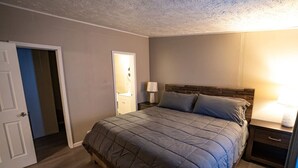 Une chambre à coucher avec un lit, des tables de chevet, une porte et un miroir.